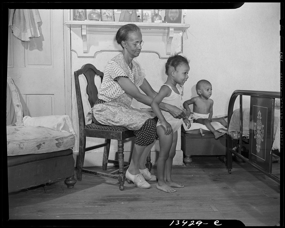 Washington, D.C. Mrs. Ella Watson, a government charwoman dressing her grandchildren. Sourced from the Library of Congress.