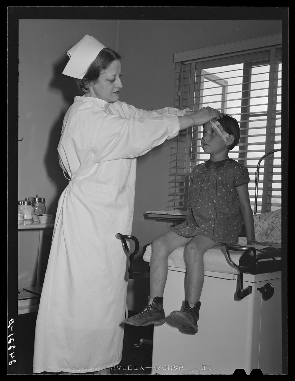 Nurse treating child in health clinic. Tulare migrant camp. Visalia, California. Sourced from the Library of Congress.