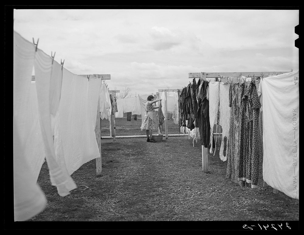 [Untitled photo, possibly related to: Woman hanging clothes to dry. Tulare migrant camp. Visalia, California]. Sourced from…