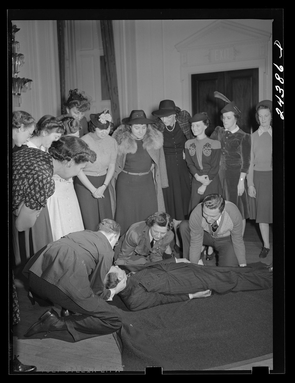 [Untitled photo, possibly related to: Civilian defense volunteers receiving instruction in proper care for man with spine…