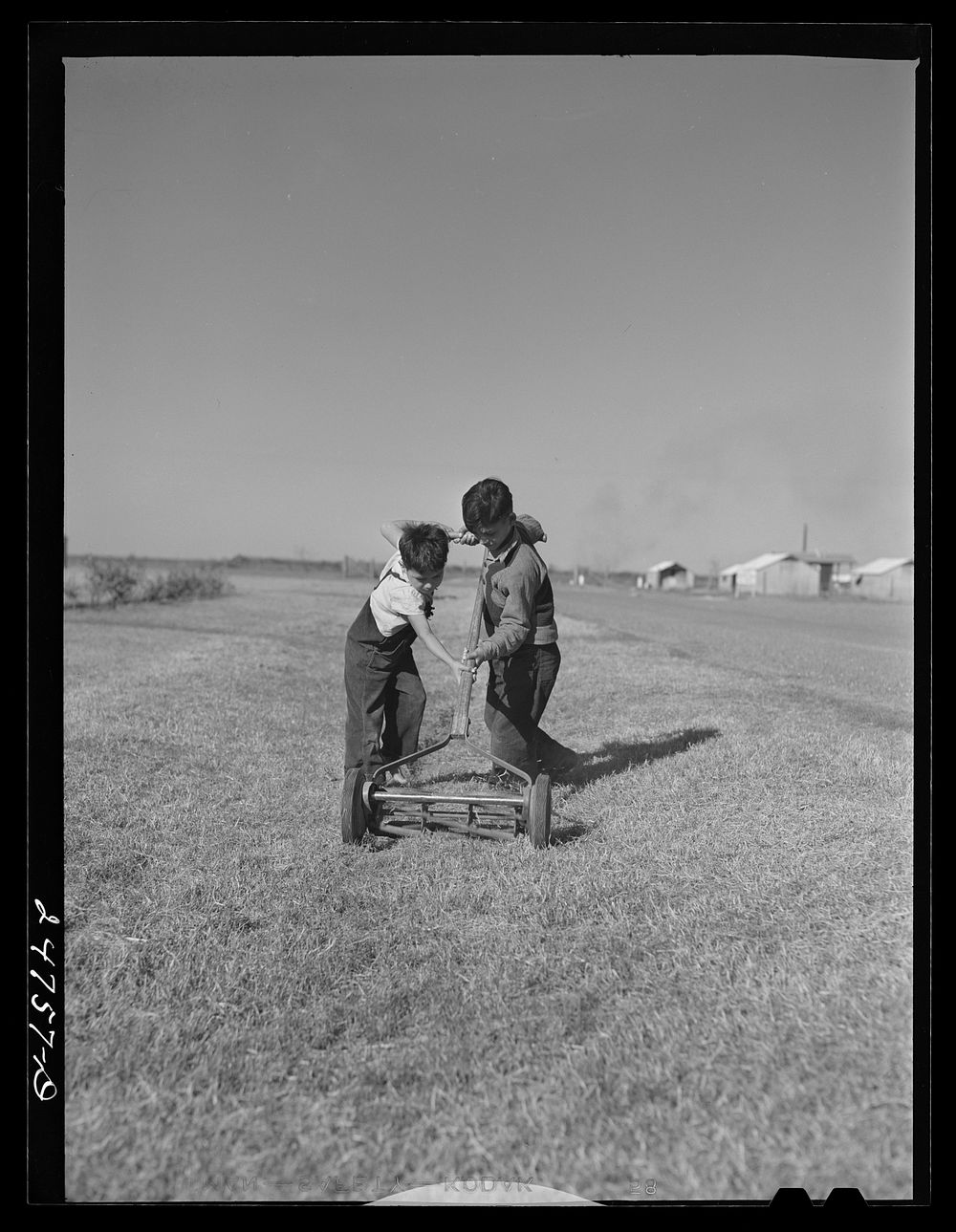Boys with community lawnmower. FSA (Farm Security Administration) camp. Robstown, Texas. Sourced from the Library of…