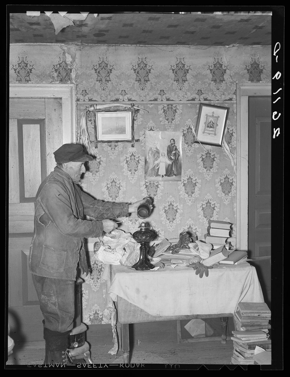 John Dudeck lighting a lamp in his home. Dalton, New York, Allegany County. Sourced from the Library of Congress.