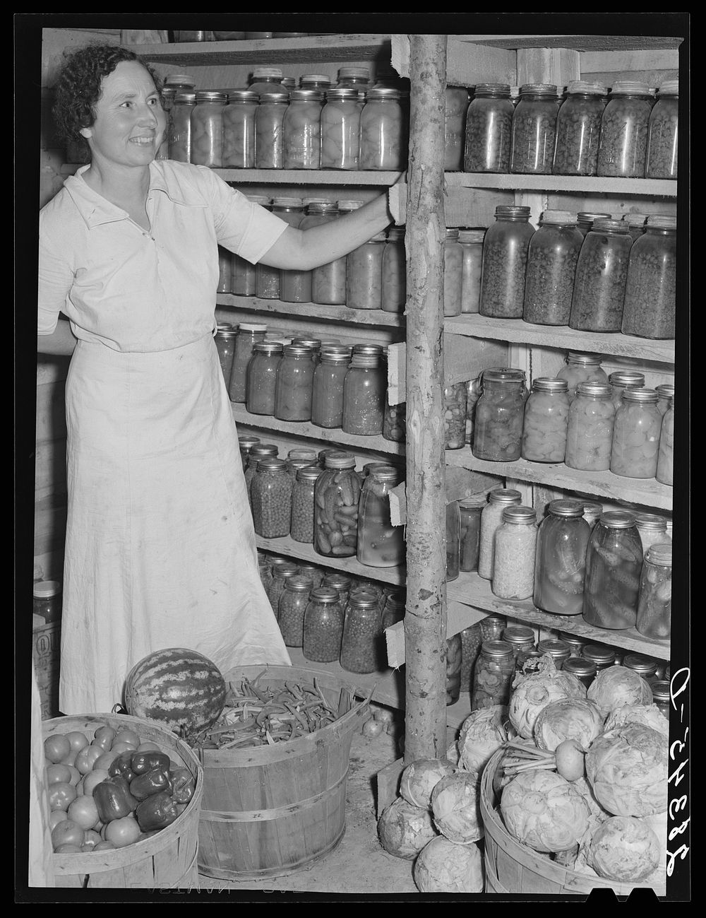 Wife of resettlement borrower, San Luis Valley Farms, Colorado, displaying fruit and vegetables preserved for winter use.…
