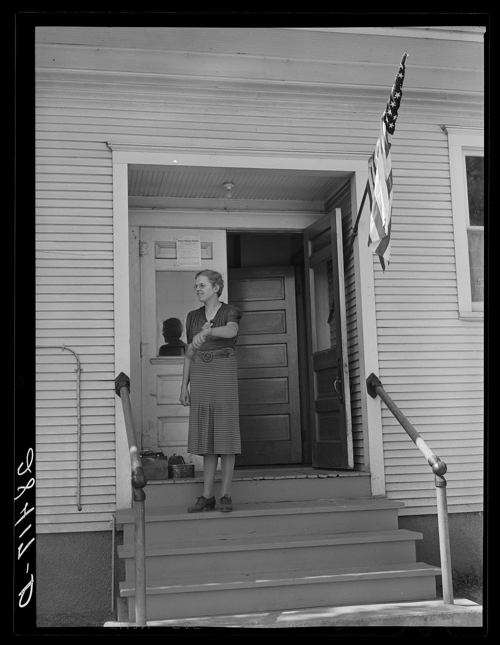 Lois Slinker, teacher of the one room school house. rings bell to end recess period. Grundy County, Iowa. Sourced from the…