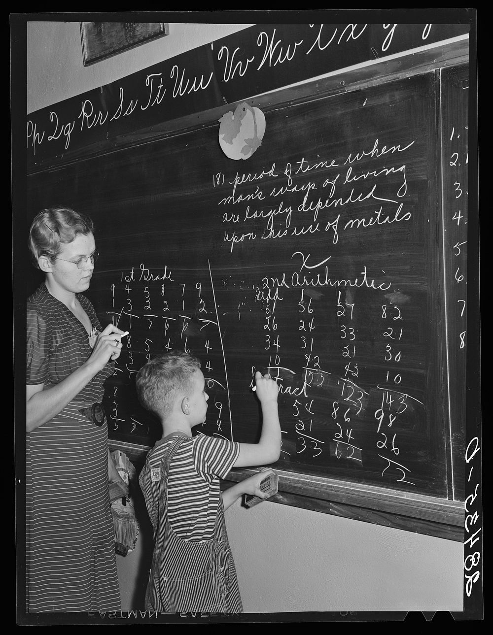 Lois Slinker teaching the only pupil in the second grade in one-room schoolhouse. Grundy County, Iowa. Sourced from the…