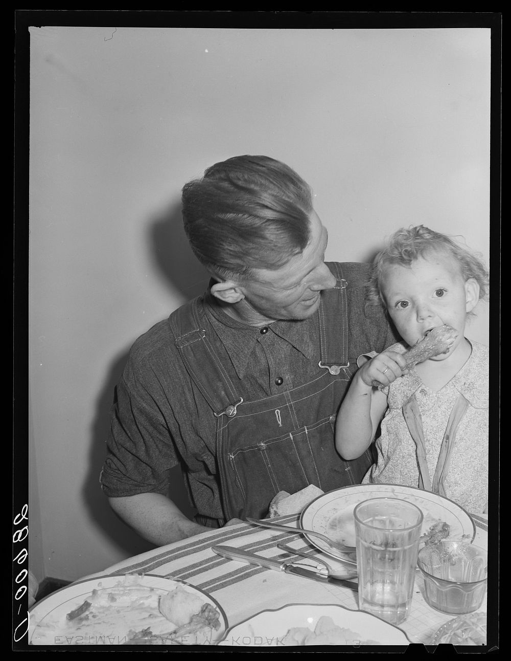 Thomas Beede and small daughter at the dinner table in their home. Western Slope Farms, Colorado. Sourced from the Library…