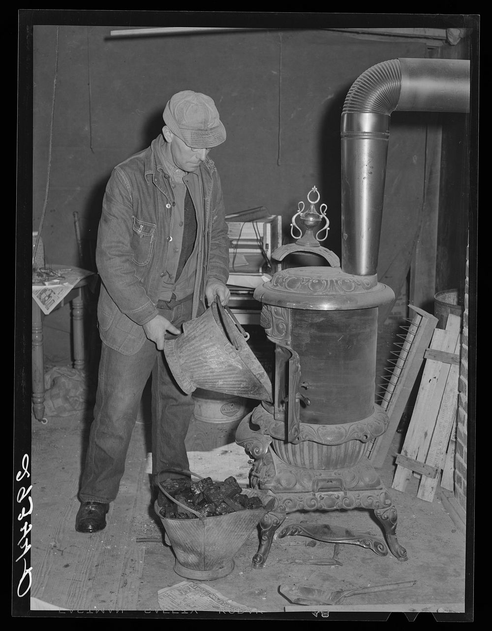 O.G. Haubeil emptying coal scuttle into stove. Ross County, Ohio. Sourced from the Library of Congress.