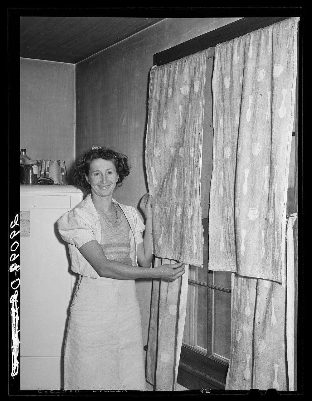 The FSA (Farm Security Administration) home supervisor has helped this woman make her dress of flour sacks and decorate her…