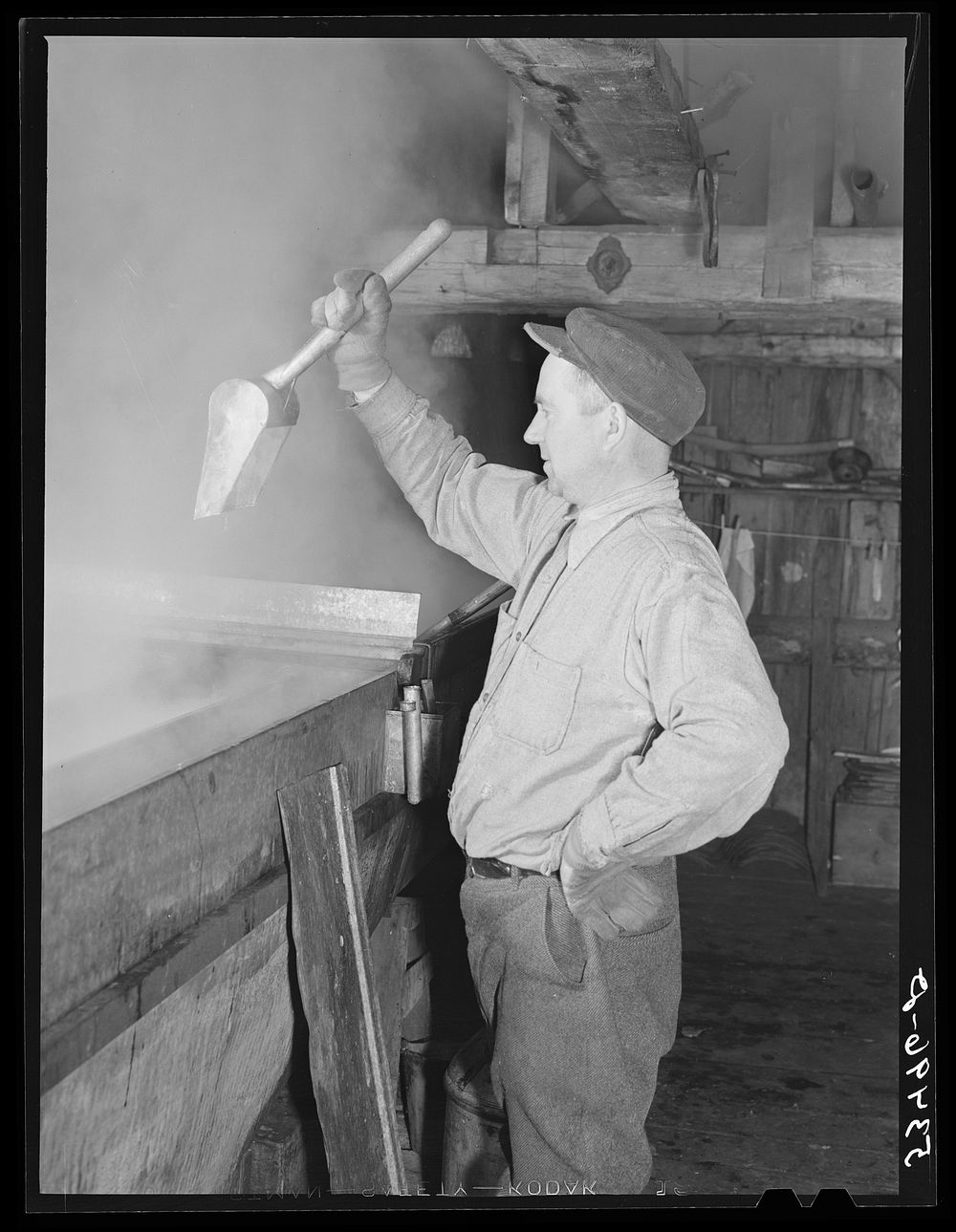 Walter. M Gaylord dripping the boiled-down maple syrup to see if it has reached the correct consistency for maple syrup.…