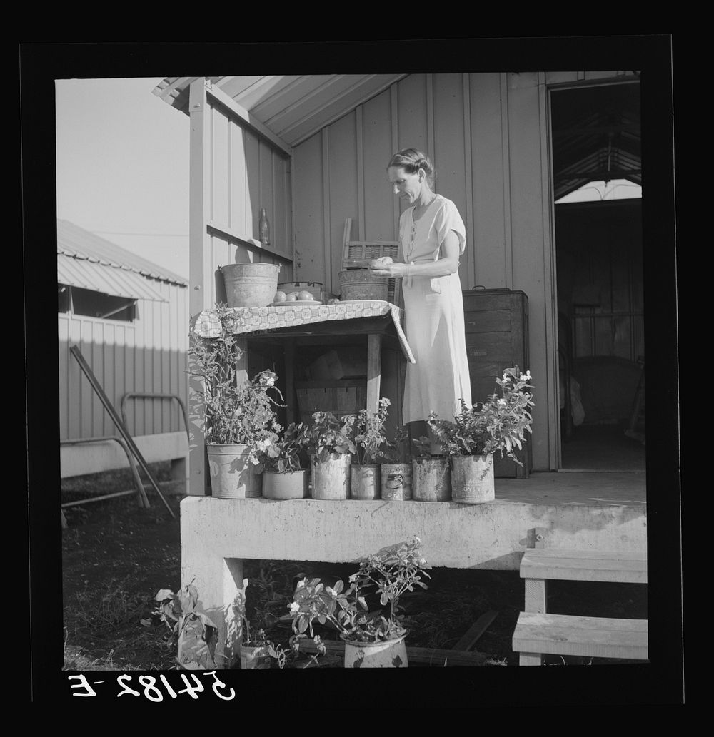 Camp member on porch of her shelter at Osceola migratory labor camp. Belle Glade, Florida. Sourced from the Library of…