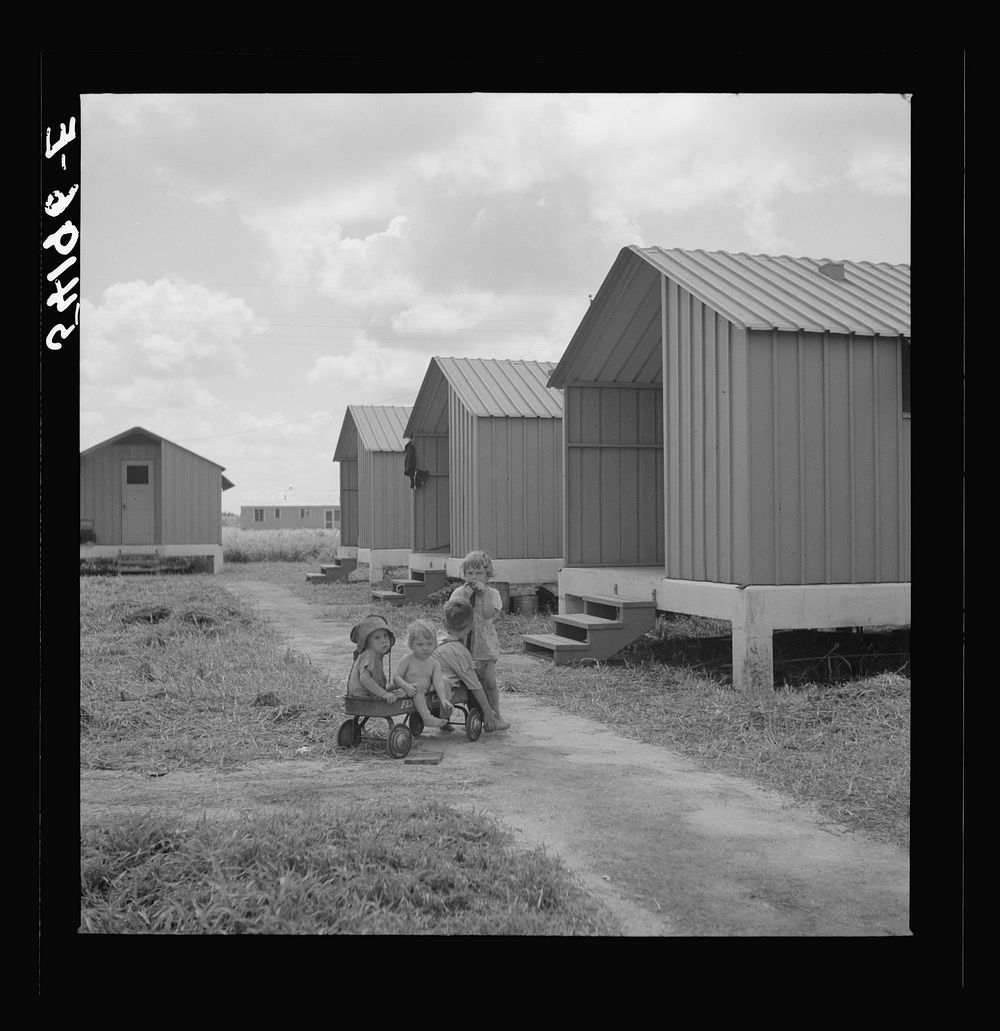[Untitled photo, possibly related to: Camp members' children playing outside their shelters at Osceola migratory labor camp.…