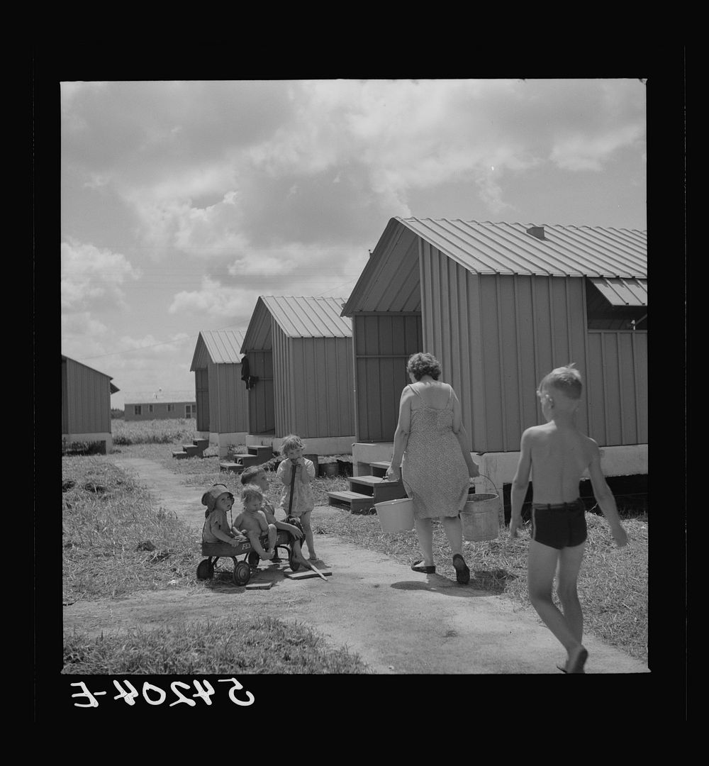 Carrying water which is easily available at head of each shelter unit at Osceola migratory labor camp. Belle Glade, Florida.…