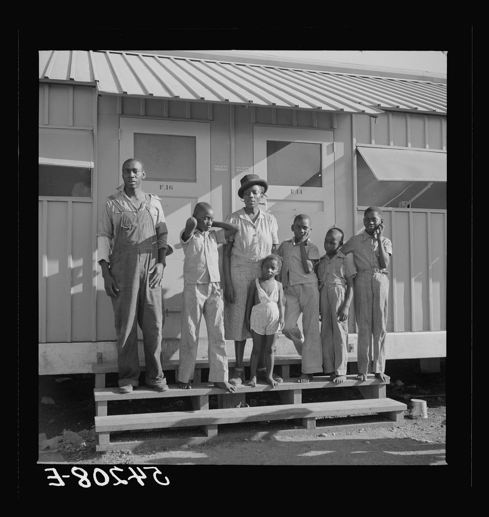 The Robinson family outside their shelter at Okeechobee migratory labor camp. Belle Glade, Florida. Sourced from the Library…