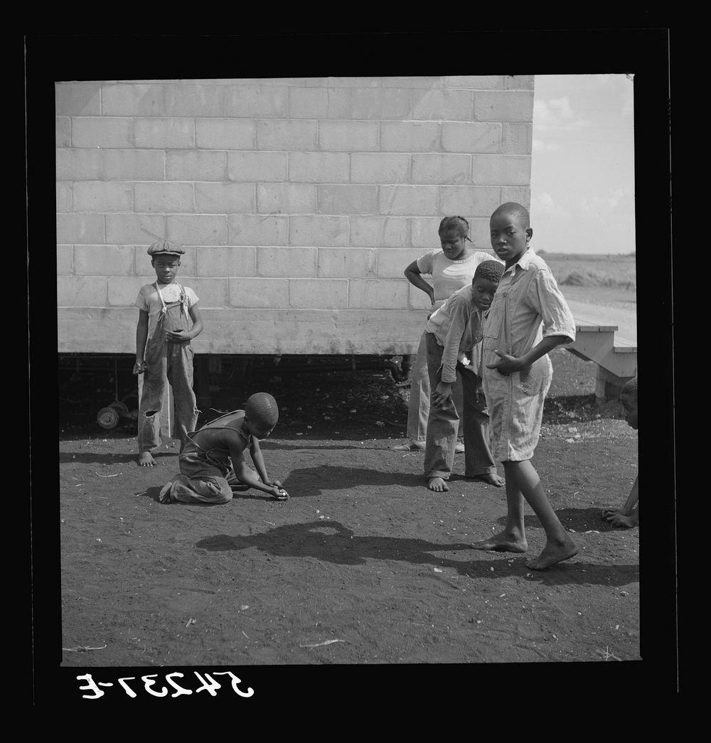 [Untitled photo, possibly related to: Camp members' children playing marbles outside their shelter units at Okeechobee…