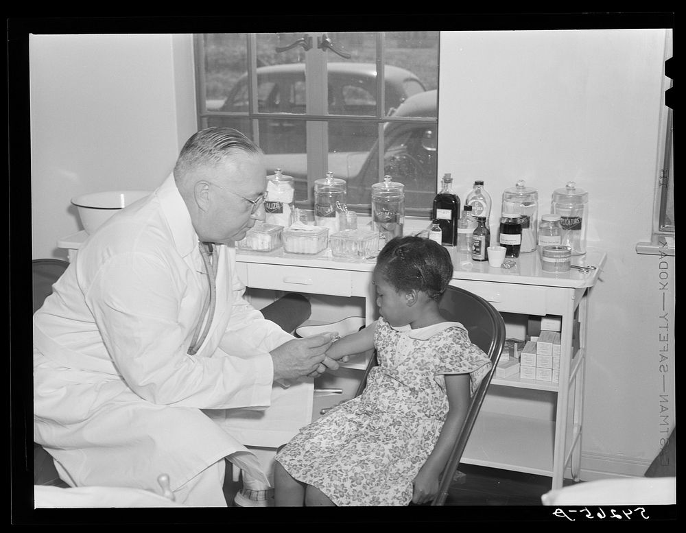 Dr. William J. Buck gives typhoid innoculation to child in clinic at Okeechobee migratory labor camp. Belle Glade, Florida.…