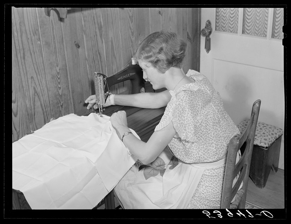 Mrs. Verden Lee sewing on her new sewing machine in her home. Transylvania Project, Louisiana. Sourced from the Library of…