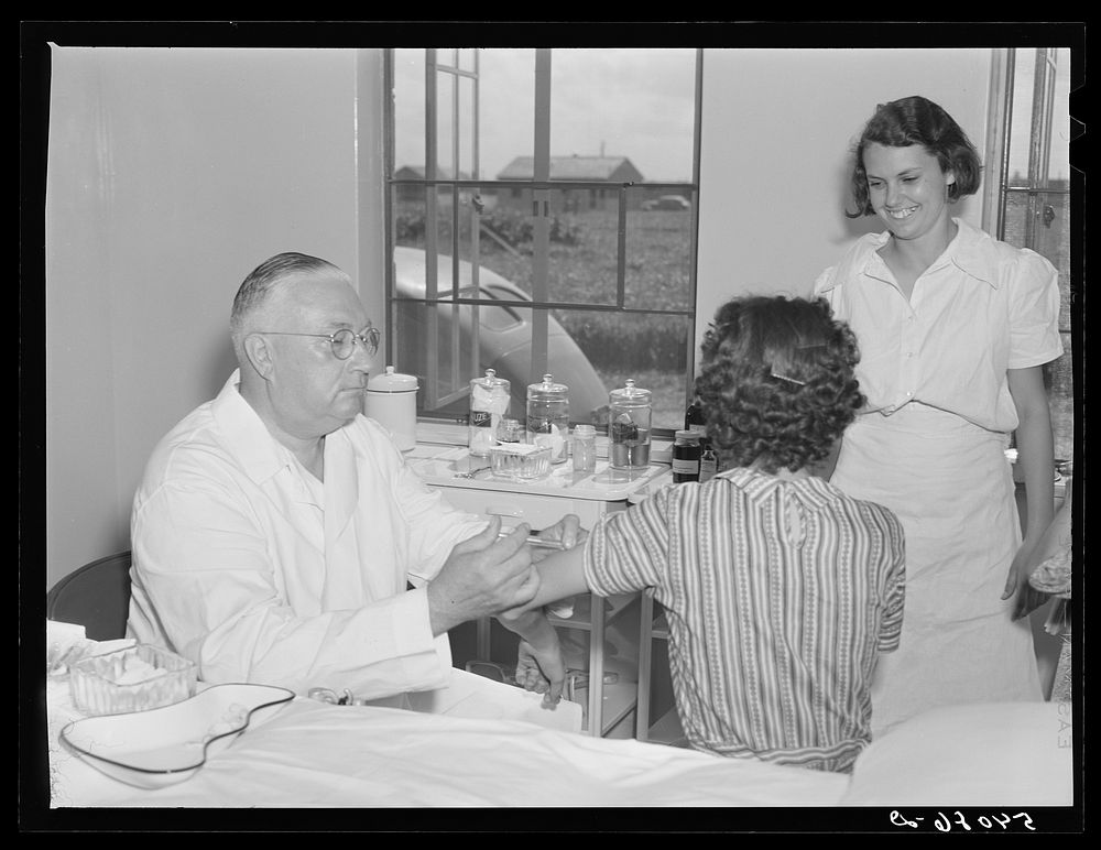Dr. William J. Buck gives typhoid shot to one of camp members with Marjory Fowler, NYA (National Youth Administration)…