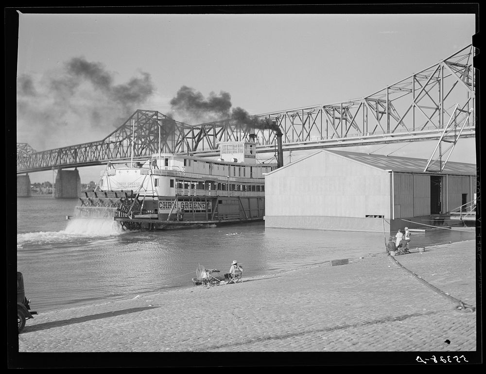 Riverboat carrying cargo leaving dock along waterfront. Louisville, Kentucky. Ohio River. Sourced from the Library of…