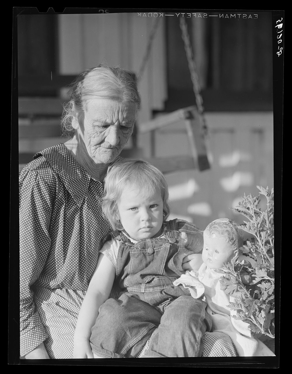 [Untitled photo, possibly related to: Mountain woman and grandchild sitting on the porch of their home up Frozen Creek…