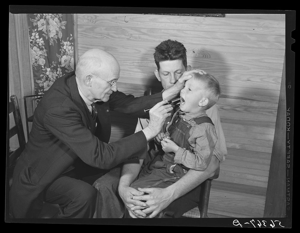 Dr. S.A. Malloy examining Mr. William H. Willis's son Bobby in their home.  Mr. Willis is a FSA (Farm Security…