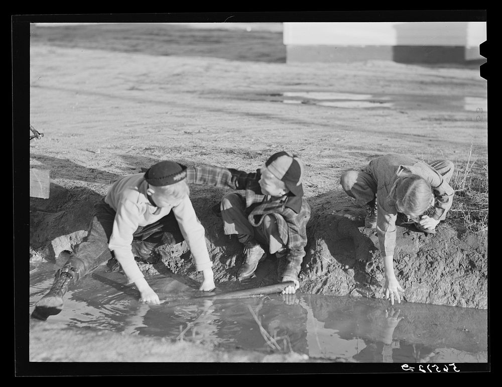 [Untitled photo, possibly related to: Children of Army men's families on Milstead Avenue playing in water in front of their…