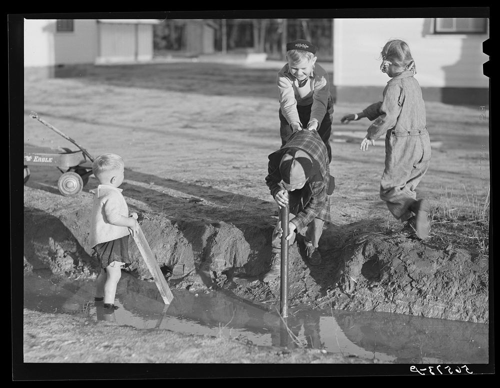 Children of Army men's families on Milstead Avenue playing in water in front of their new homes five miles outside of…