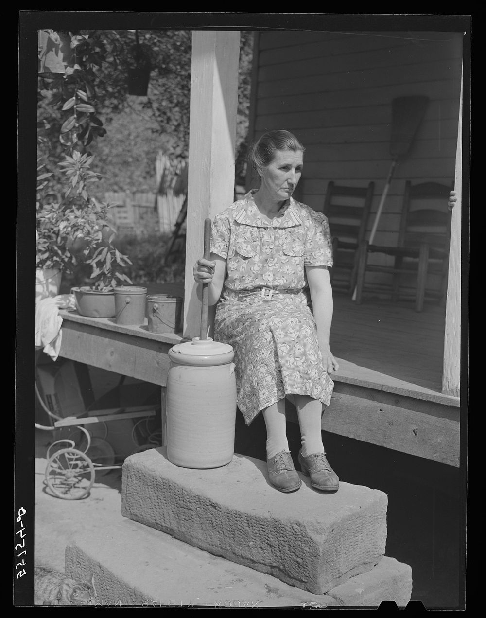 Mountain woman churning butter on the steps of front porch of her home. Up Burton's Fork off Middle Fork of the Kentucky…