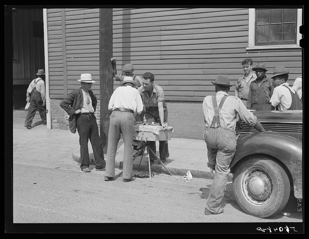 Peddler selling patent medicines to farmers outside warehouse on opening day of tobacco market in Mebane, North Carolina…
