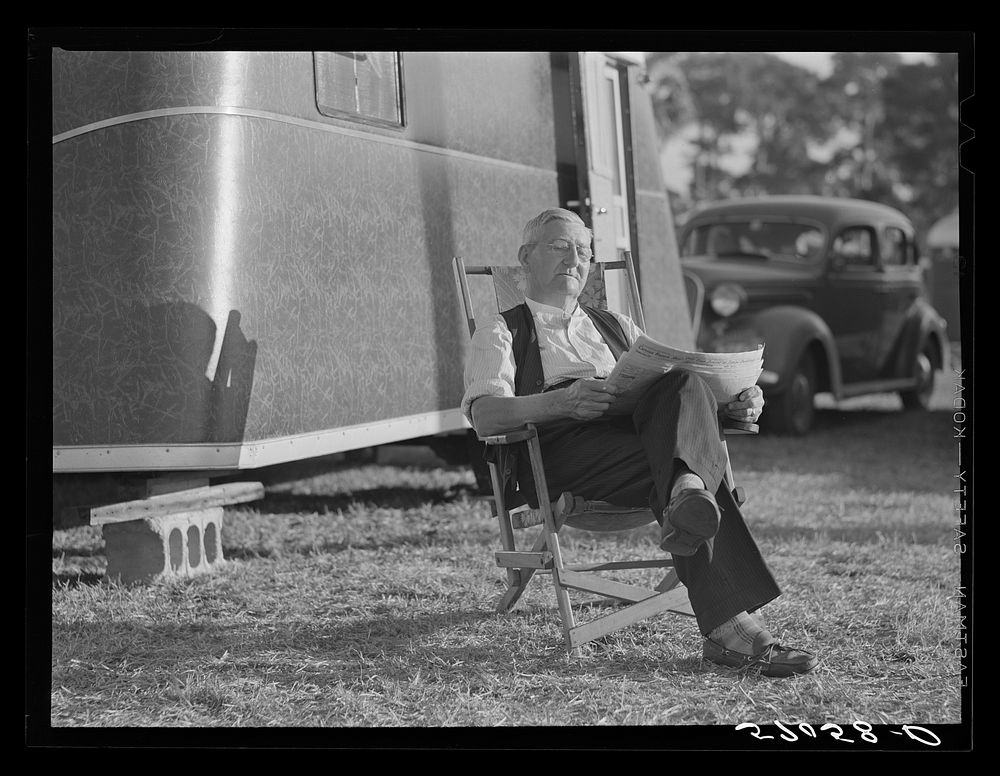 Reading the newspaper outside his trailer home. Sarasota trailer park, Sarasota, Florida. Sourced from the Library of…