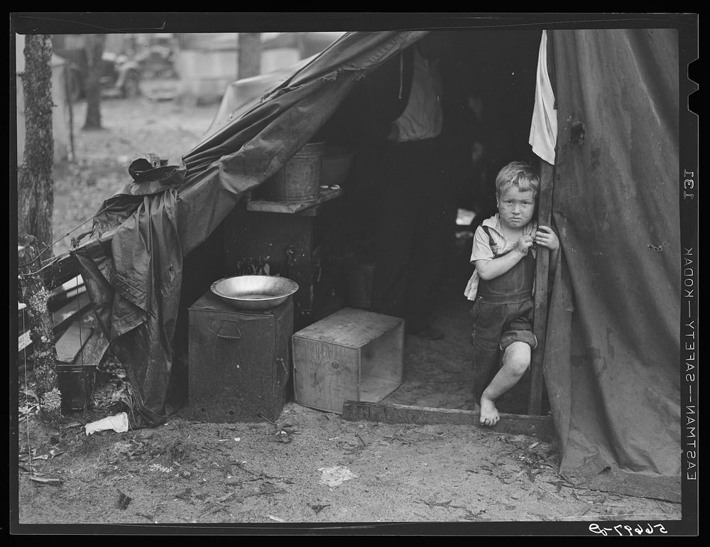 Child of construction worker in doorway of tent home near Alexandria, Louisiana. Ten men, two women, and two children live…
