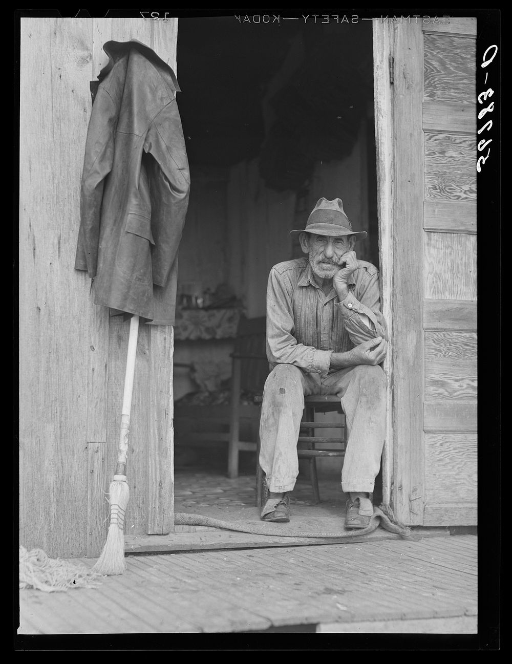 Spanish muskrat trapper in doorway of his marsh camp. Delacroix Island, Saint Bernard Parish, Louisiana. Sourced from the…
