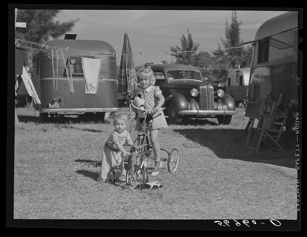 Children playing outside their trailer home at Sarasota trailer park. Sarasota, Florida. Sourced from the Library of…