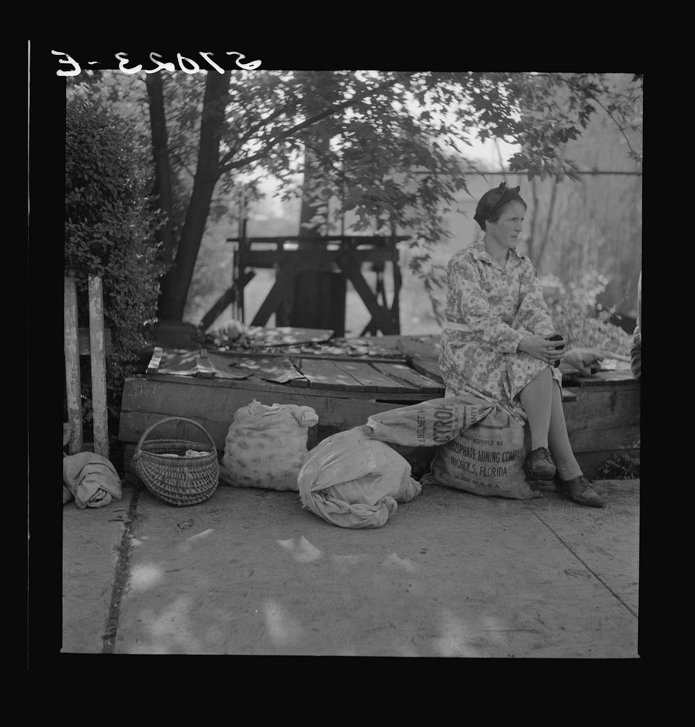 Mountain woman with groceries and supplies resting by roadside. Jackson, Breathitt County, Kentucky. Sourced from the…