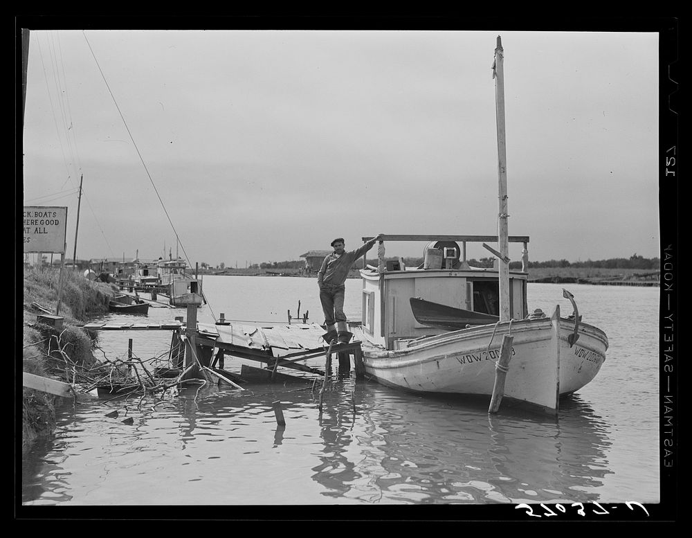 Spanish muskrat trapper standing beside his boat used to go out of the camp in the marshes and for fishing in other seasons.…
