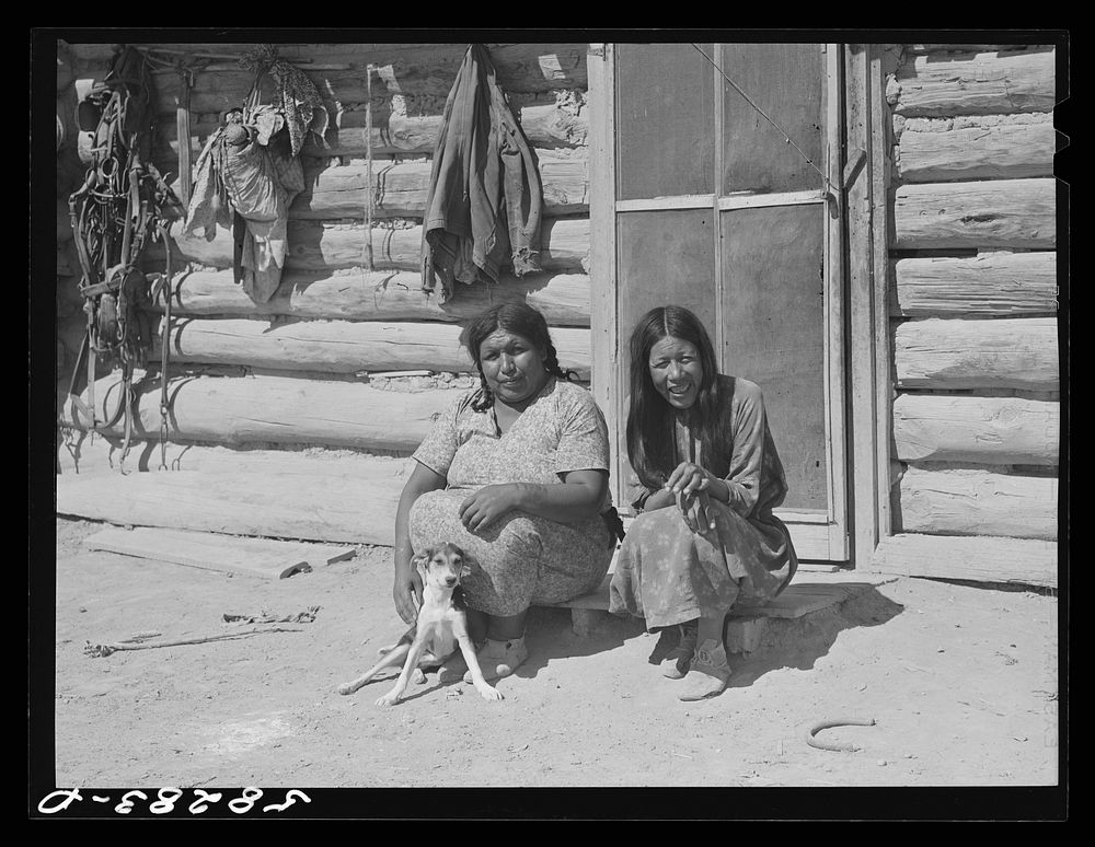 Cheyenne Indians in front of their log hut, their "medicine" hanging on wall. Near Lame Deer, Montana. Sourced from the…
