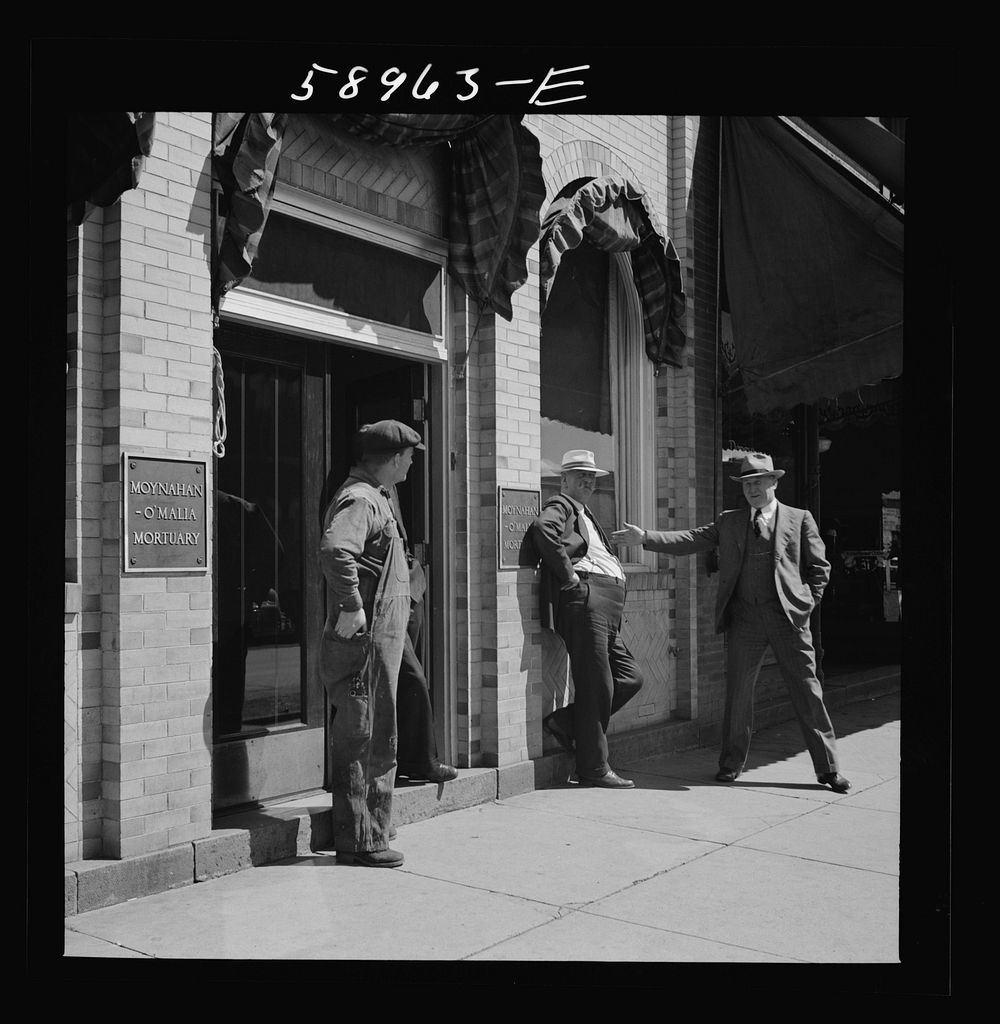[Untitled photo, possibly related to: County judge with mortician and workman in front of mortuary. Main street of…