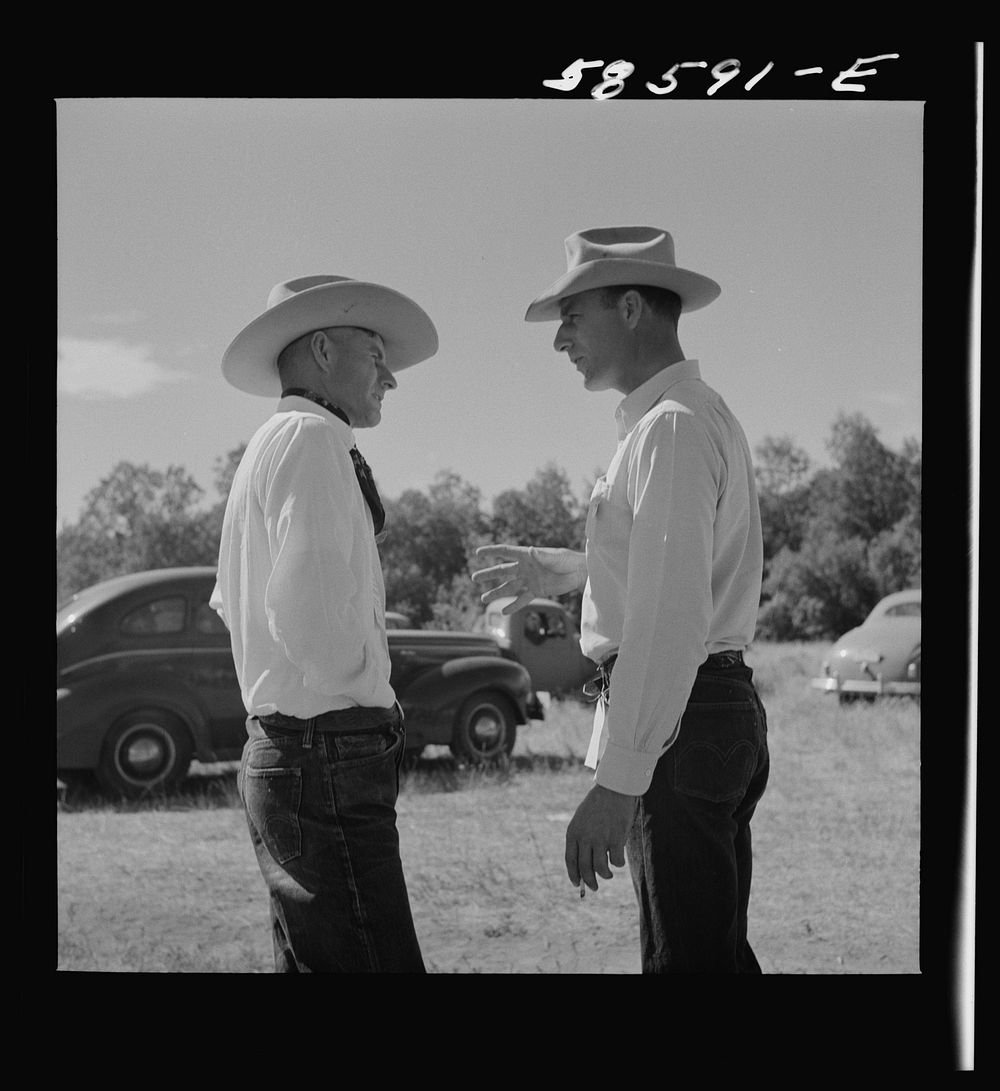 [Untitled photo, possibly related to: Lyman Brewster from Quarter Circle U Ranch in Birney, Montana, talking to a neighbor…
