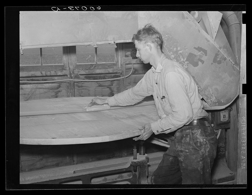 Homesteader planing a table in the woodworking shop. Tygart Valley Homesteads, West Virginia. Sourced from the Library of…