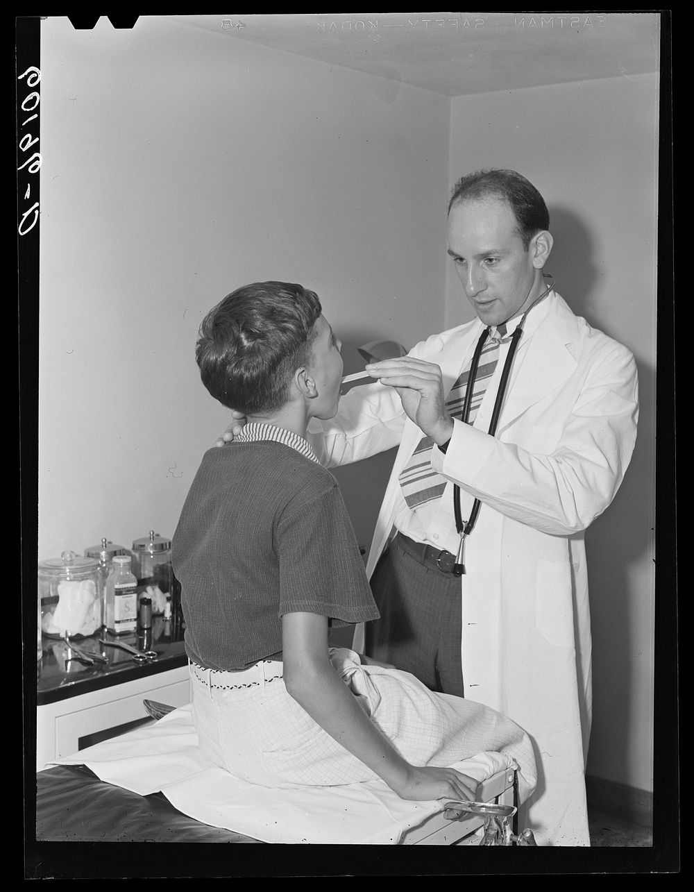 Doctor examining boy's throat. Greendale, Wisconsin. This is the Greendale branch of the Milwaukee Group Health Association.…