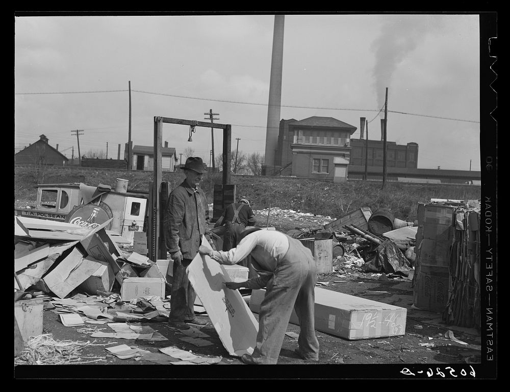 Baling papers and cardboard boxes salvaged from the city dump. Dubuque, Iowa. These men live in shacks just on the edge of…