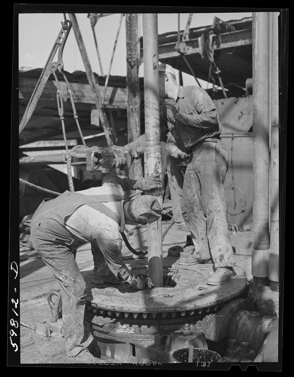 [Untitled photo, possibly related to: Oil workers pulling up old pipe to change bit on drilling pipe at bottom of oil well…