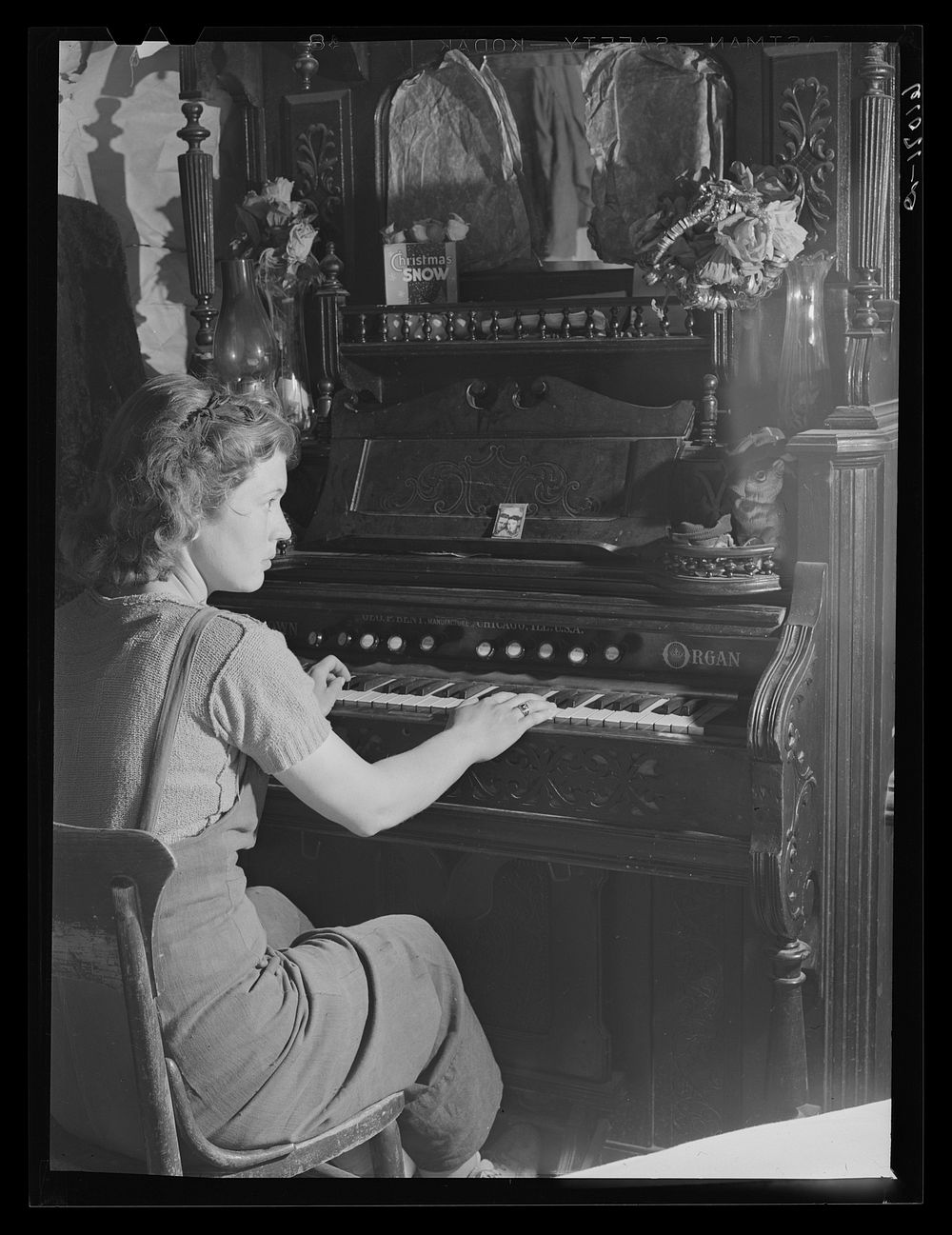 Girl playing organ in shack home on poor land along riverbottoms. Her family will move to one of the Delmo labor homes. New…