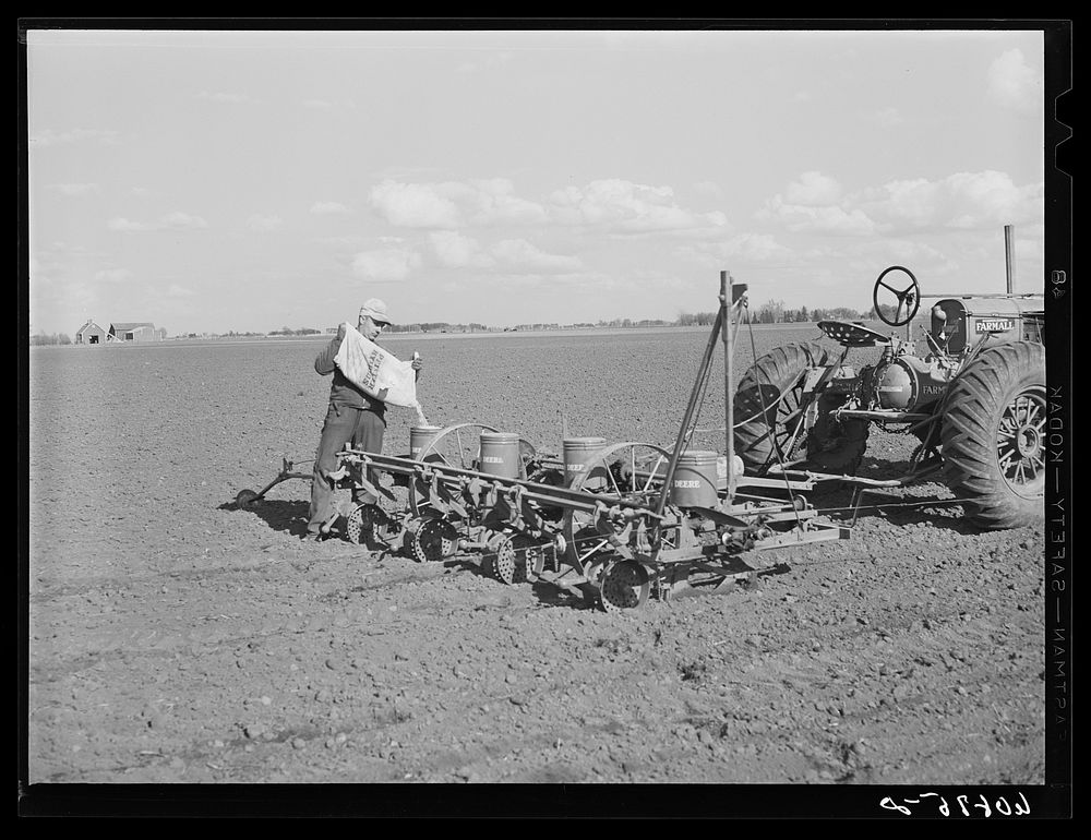 Pouring hybrid seed corn in box of four-row tractor planter. Jasper County, Iowa. Sourced from the Library of Congress.