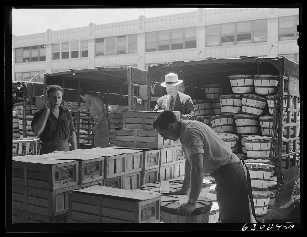 Commission merchant supervising unloading of truck at produce market. Chicago, Illinois. Sourced from the Library of…