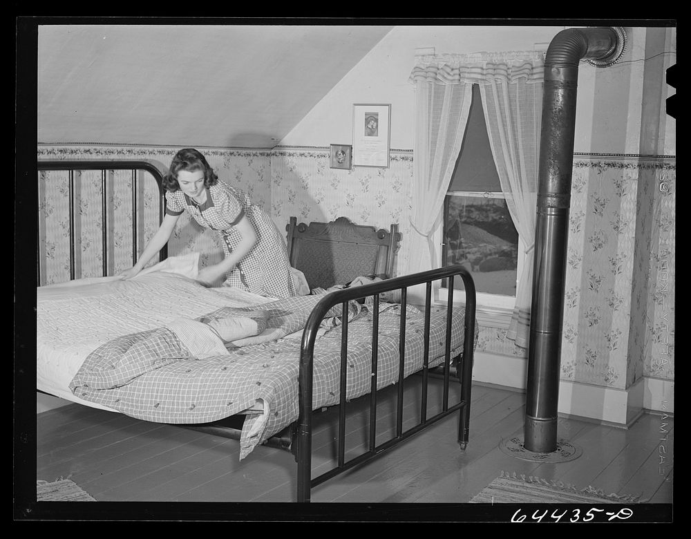 Meeker County, Minnesota. Elaine McCormick, one of the McRaith grandchildren, making the beds in the morning before the…