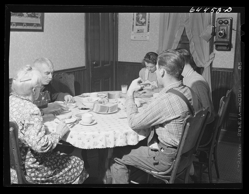 Meeker County, Minnesota. Old Mr. and Mrs. McRaith, Pat, the hired man, and one of the grandchildren at lunch. Sourced from…