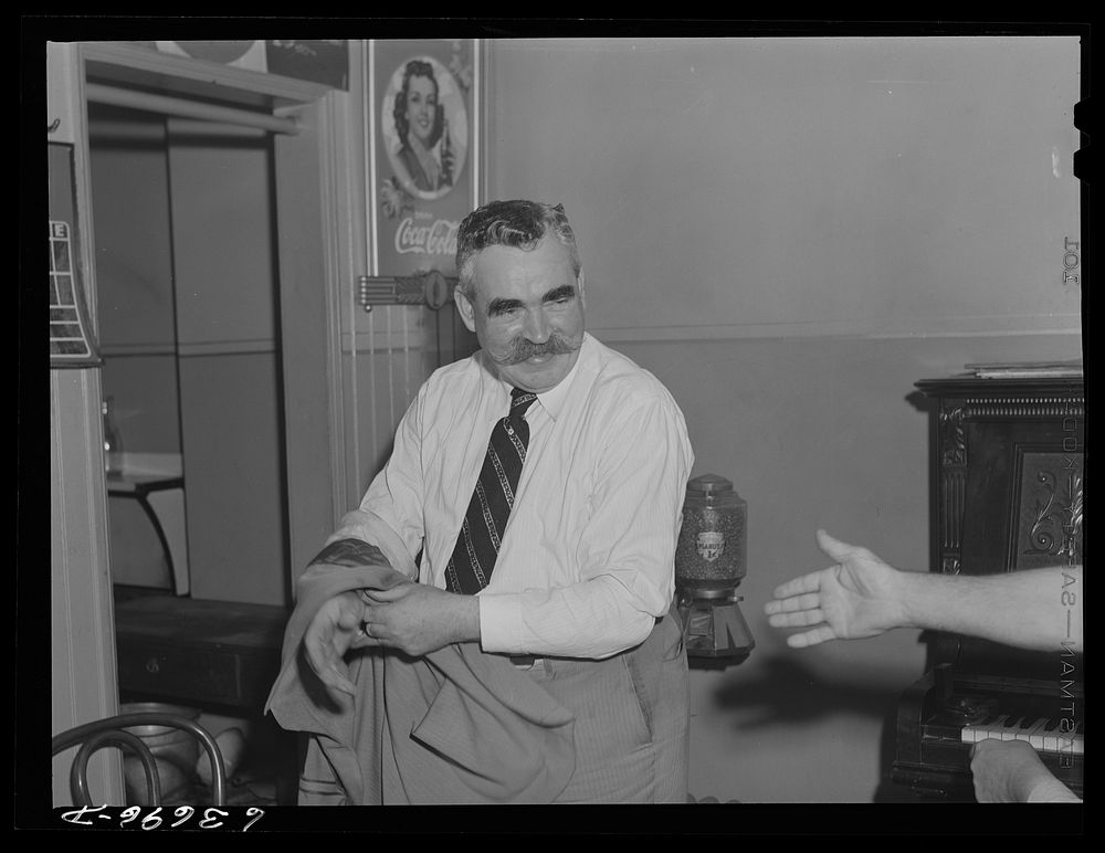 Jack Dwyer taking off his coat in a saloon. Detroit, Michigan. Sourced from the Library of Congress.