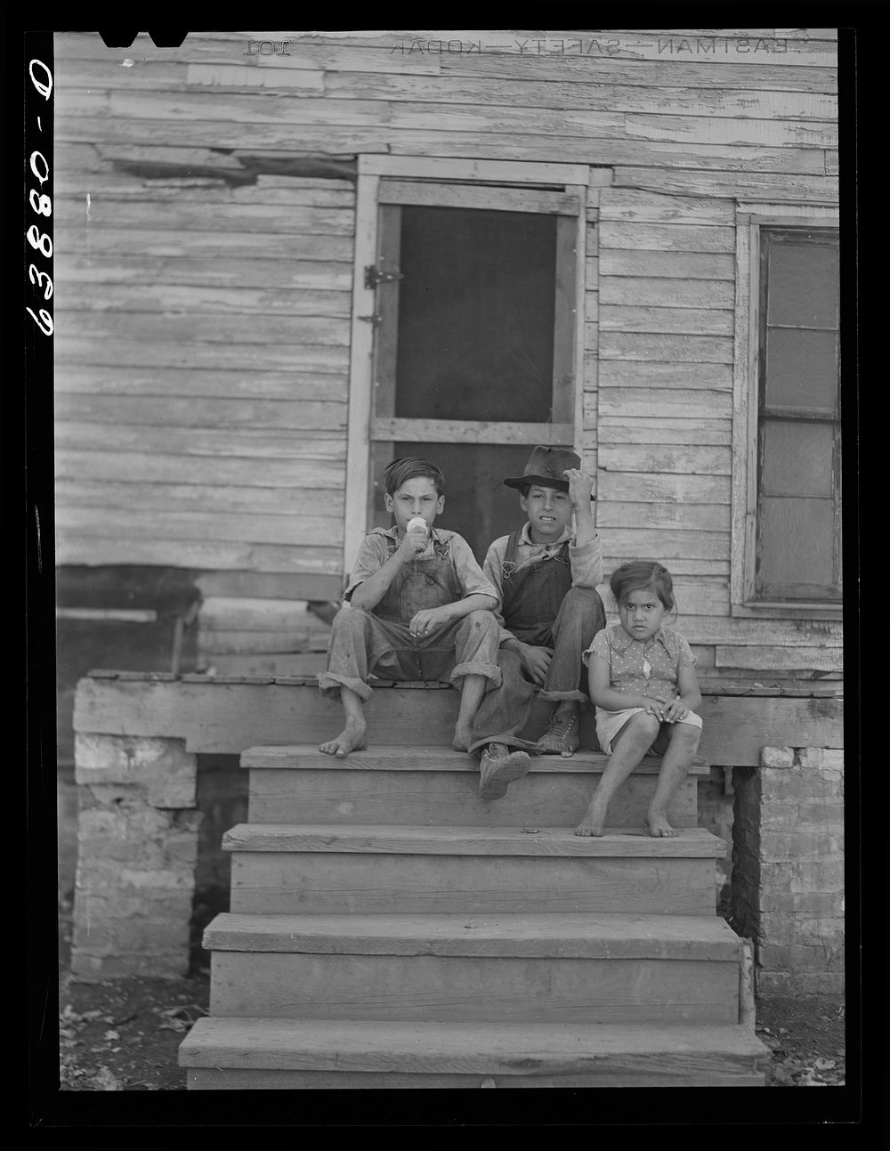 Children of Mexican sugar beet workers on porch of one of the houses at Saginaw Farms, Michigan. Sourced from the Library of…