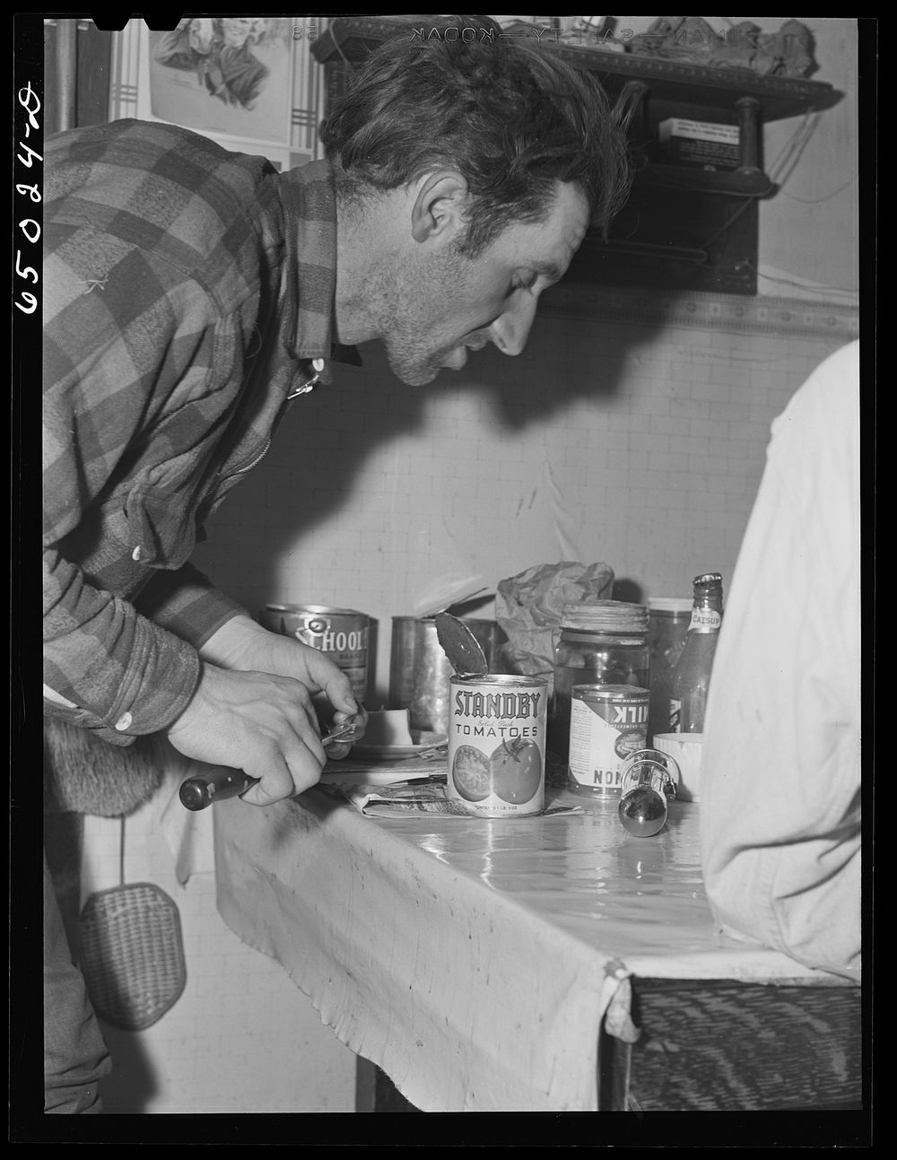 Garfield County, Montana. Sheepherder opening cans for supper in his winter quarters. Sourced from the Library of Congress.