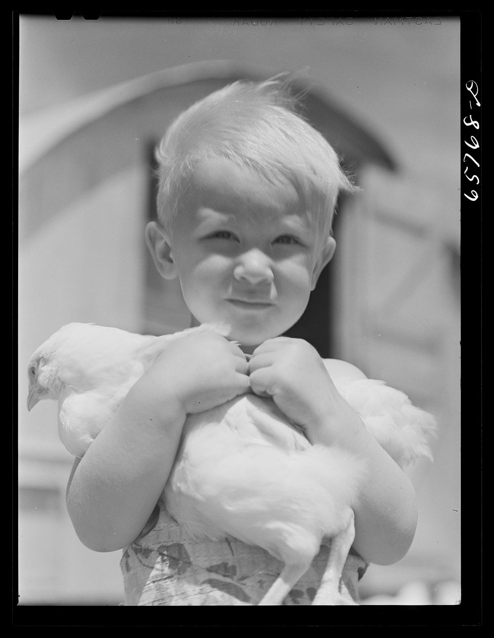 [Untitled photo, possibly related to: Lancaster County, Nebraska. Mrs. Lynn May's son carrying a chicken]. Sourced from the…